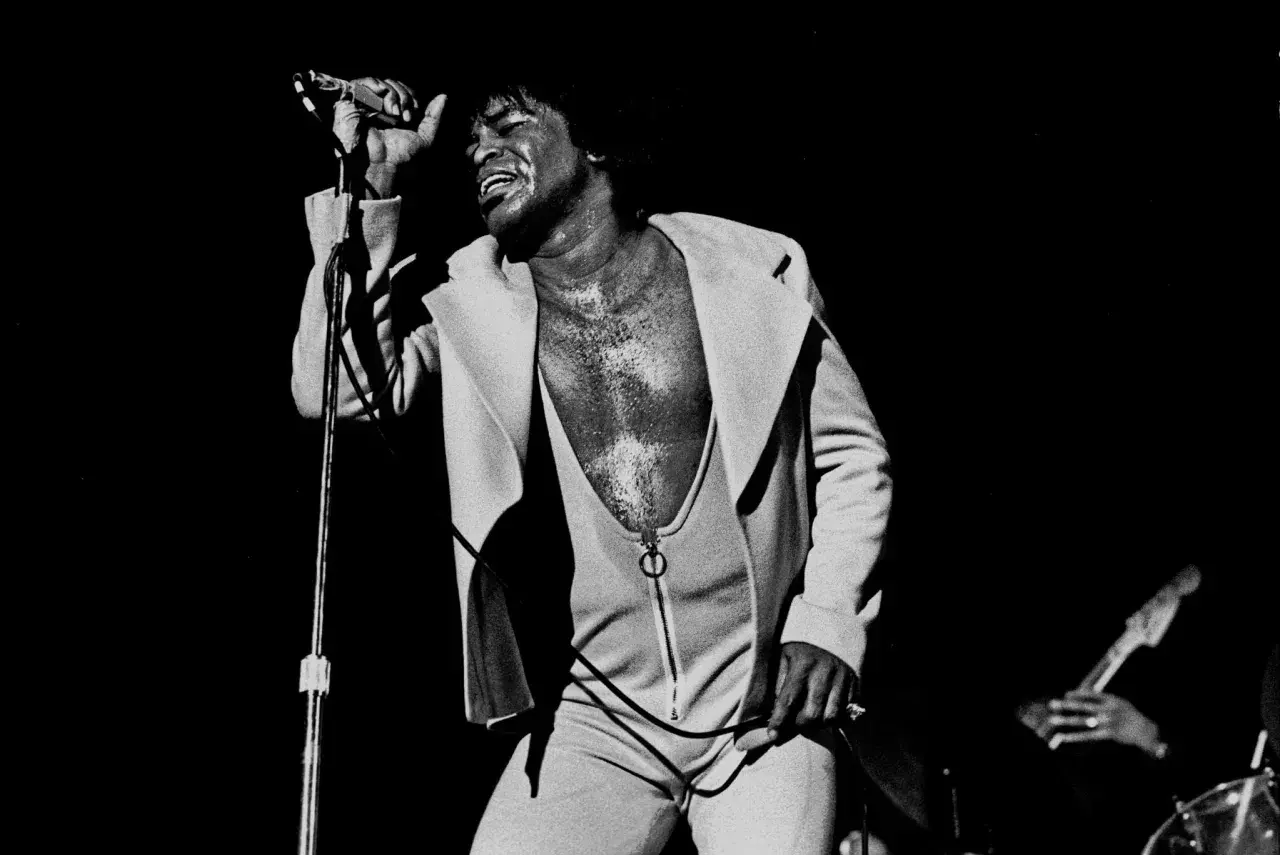 James Brown singt mit geschlossenen Augen und erhobener Hand, ein ikonisches Bild, das an bekannte Funk-Songs erinnert.