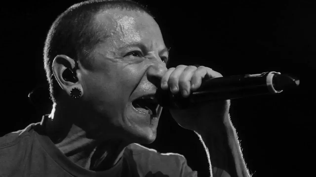 Linkin Park's Chester Bennington singt mit voller Leidenschaft ins Mikrofon, Schweißperlen auf der Stirn.