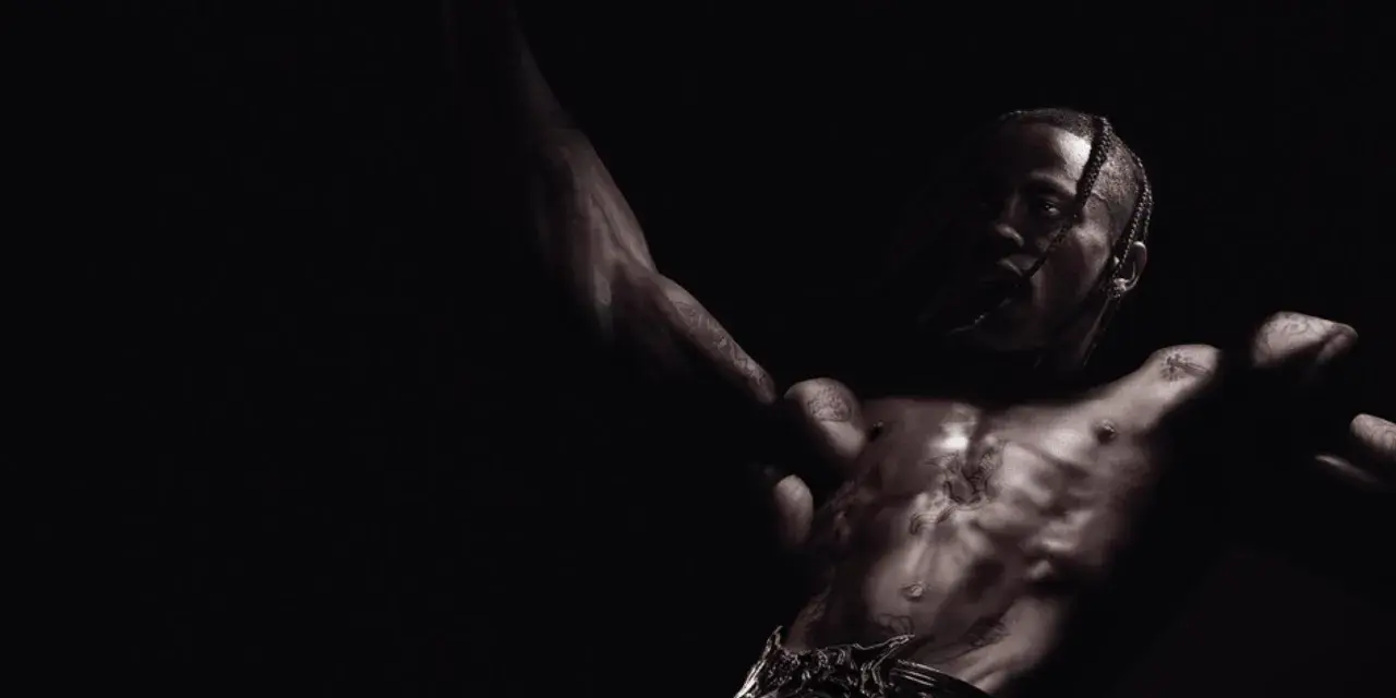 Travis Scott, mit tätowiertem Oberkörper, streckt die Arme aus und blickt intensiv in die Kamera. Ein Moment der rohen Energie, der an Travis' Utopia erinnert.