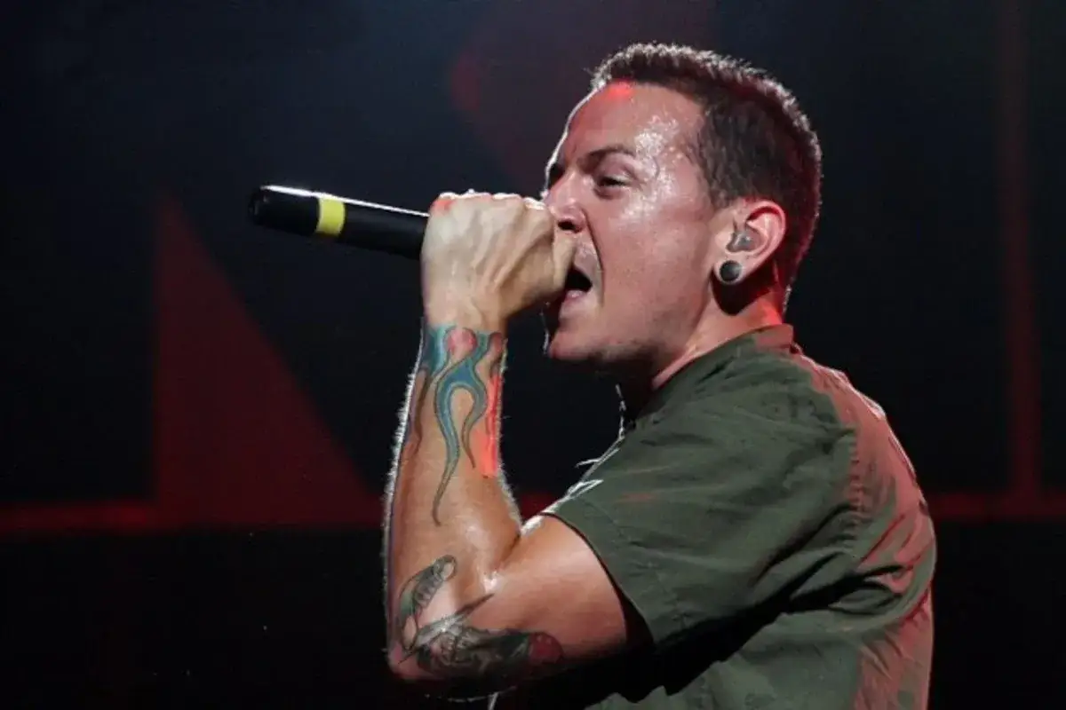 Linkin Park Chester Bennington singt mit Leidenschaft ins Mikrofon, Schwei&szlig; auf der Stirn, t&auml;towierte Arme.