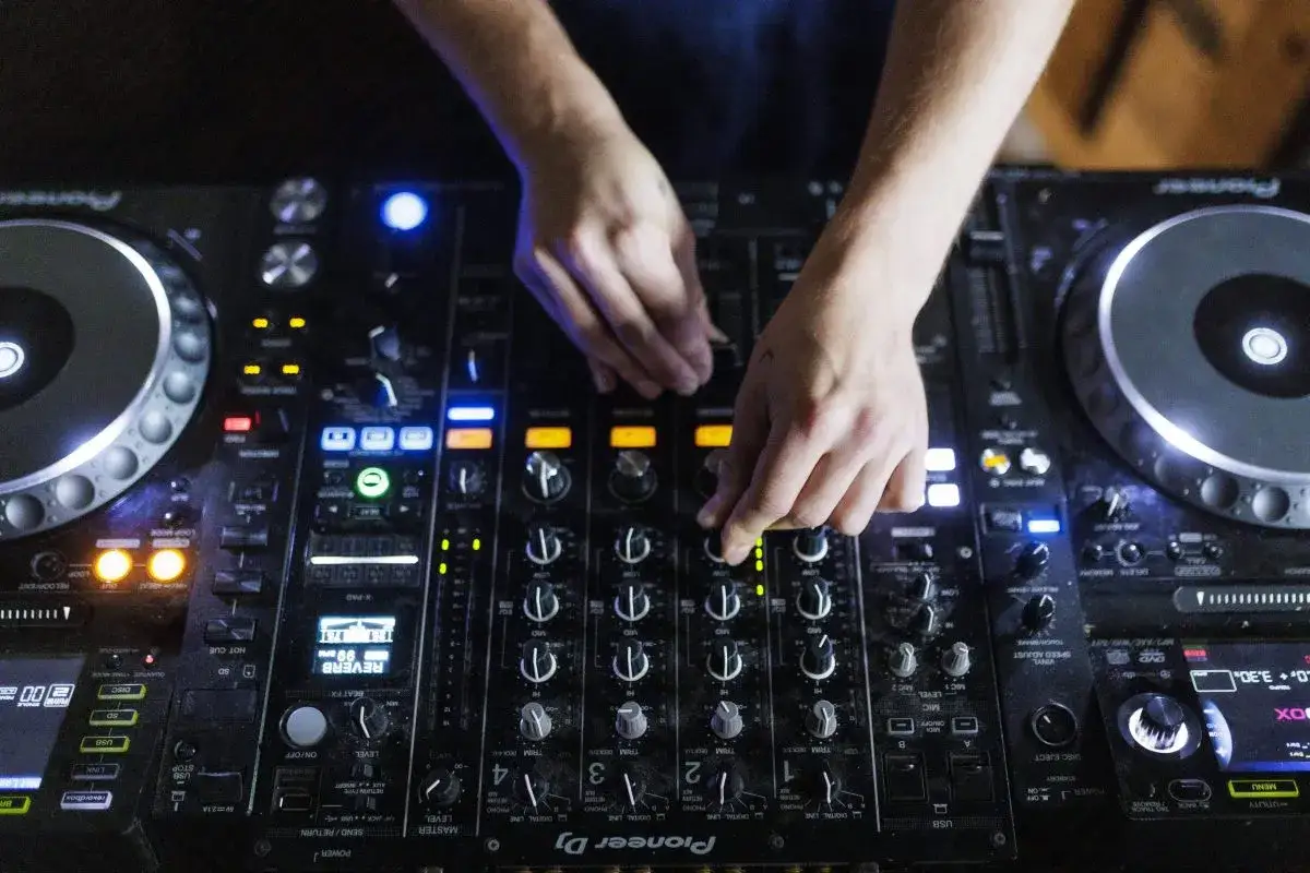 H&auml;nde eines live DJ am Mischpult, der die Regler bedient und die Musik mixt.