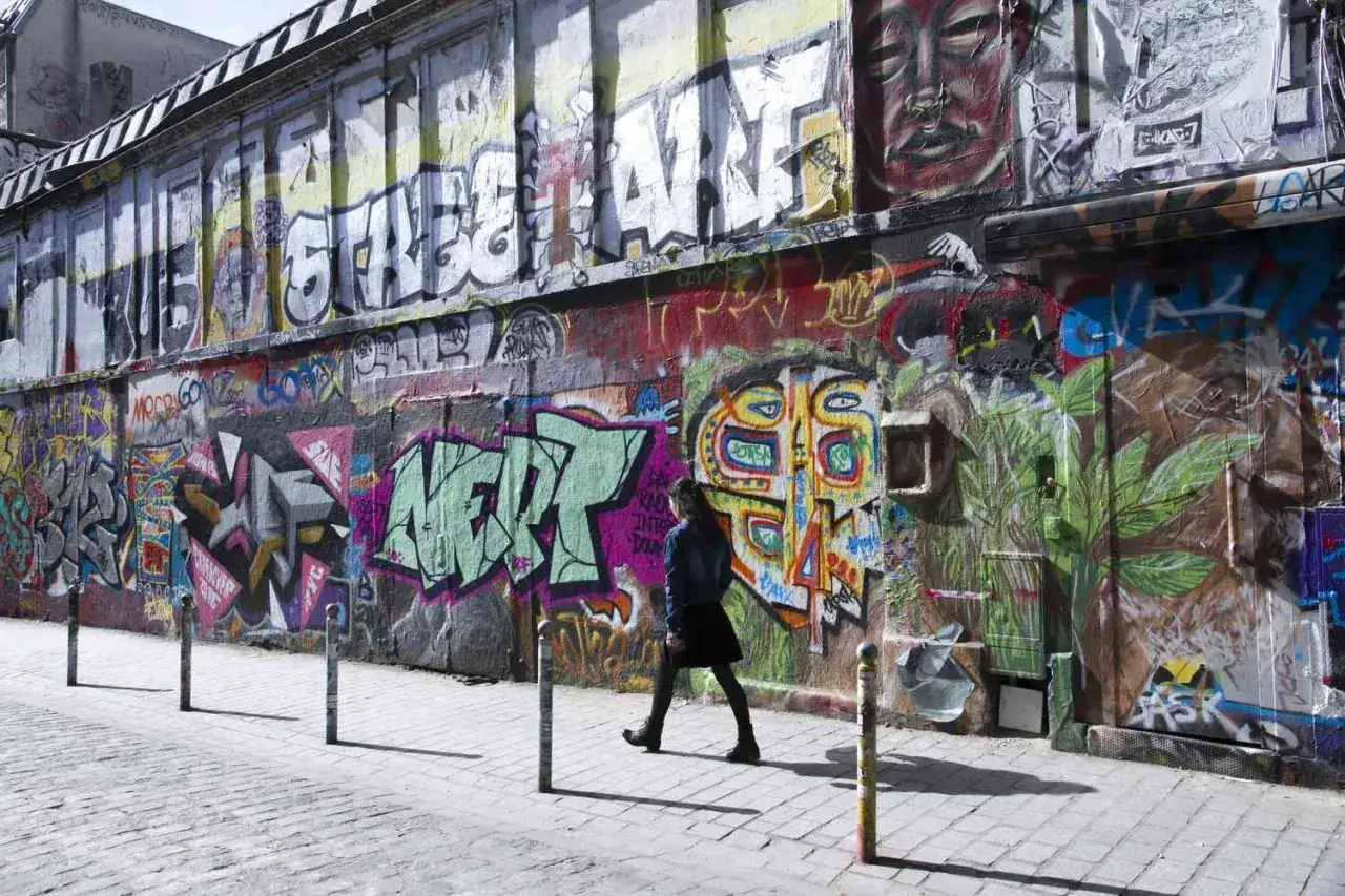 Bunte Paris street art bedeckt eine Wand, w&auml;hrend eine Person vorbeigeht.
