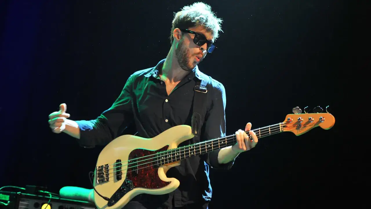 Joe Dart, mit Sonnenbrille und dunklem Hemd, spielt energisch auf seinem wei&szlig;en Bass.
