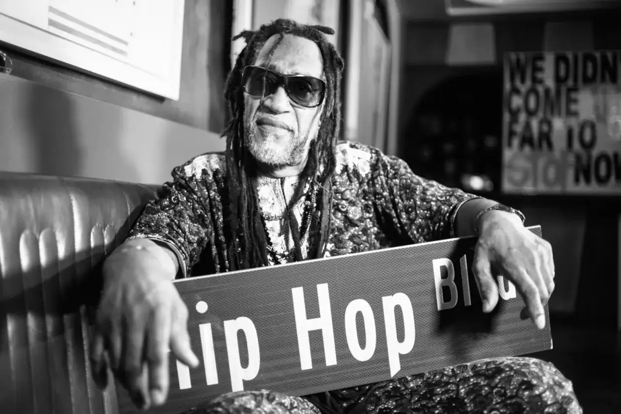 Ein Mann mit Dreadlocks und Sonnenbrille h&auml;lt ein Schild mit 