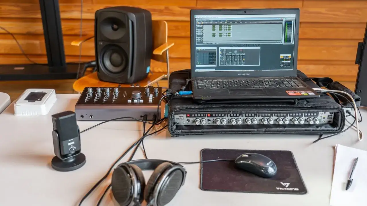 Ein Audient iD44 Audio-Interface mit Laptop, Monitorlautsprecher, Mikrofon und Kopfh&ouml;rern f&uuml;r Musikproduktion.