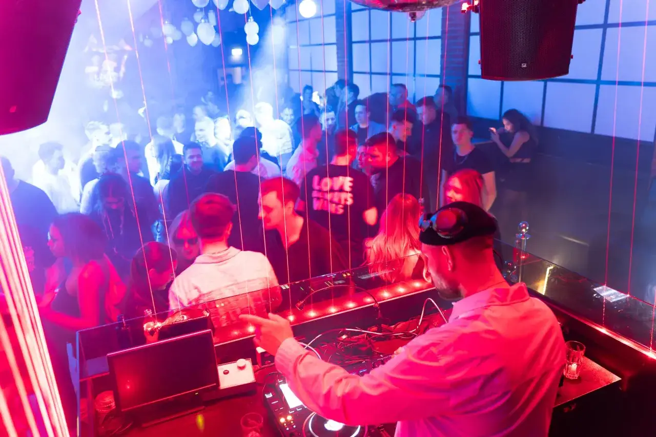 DJ legt auf, die Menge tanzt im roten und blauen Licht. Ein perfekter dj mix f&uuml;r eine ausgelassene Nacht.