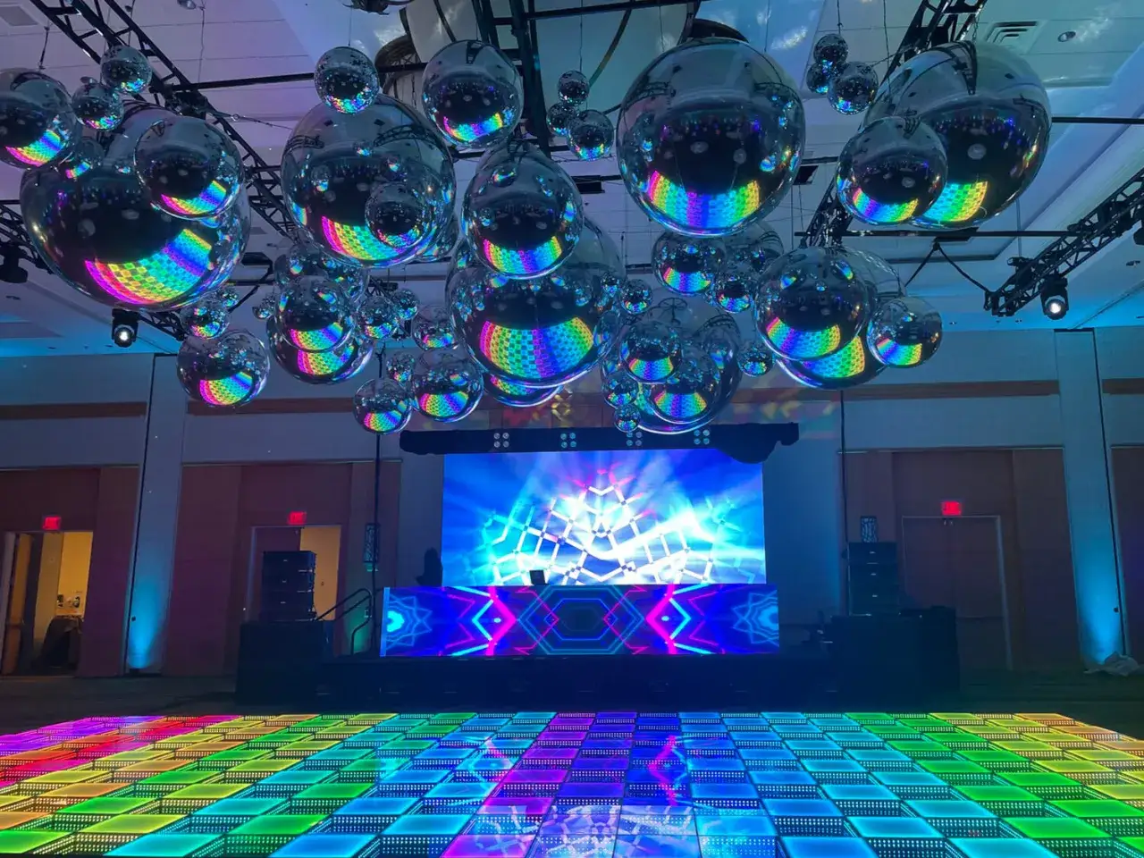Glitzernde Discokugeln hängen über einer bunten Tanzfläche, bereit für einen Abend voller deep house Musik.