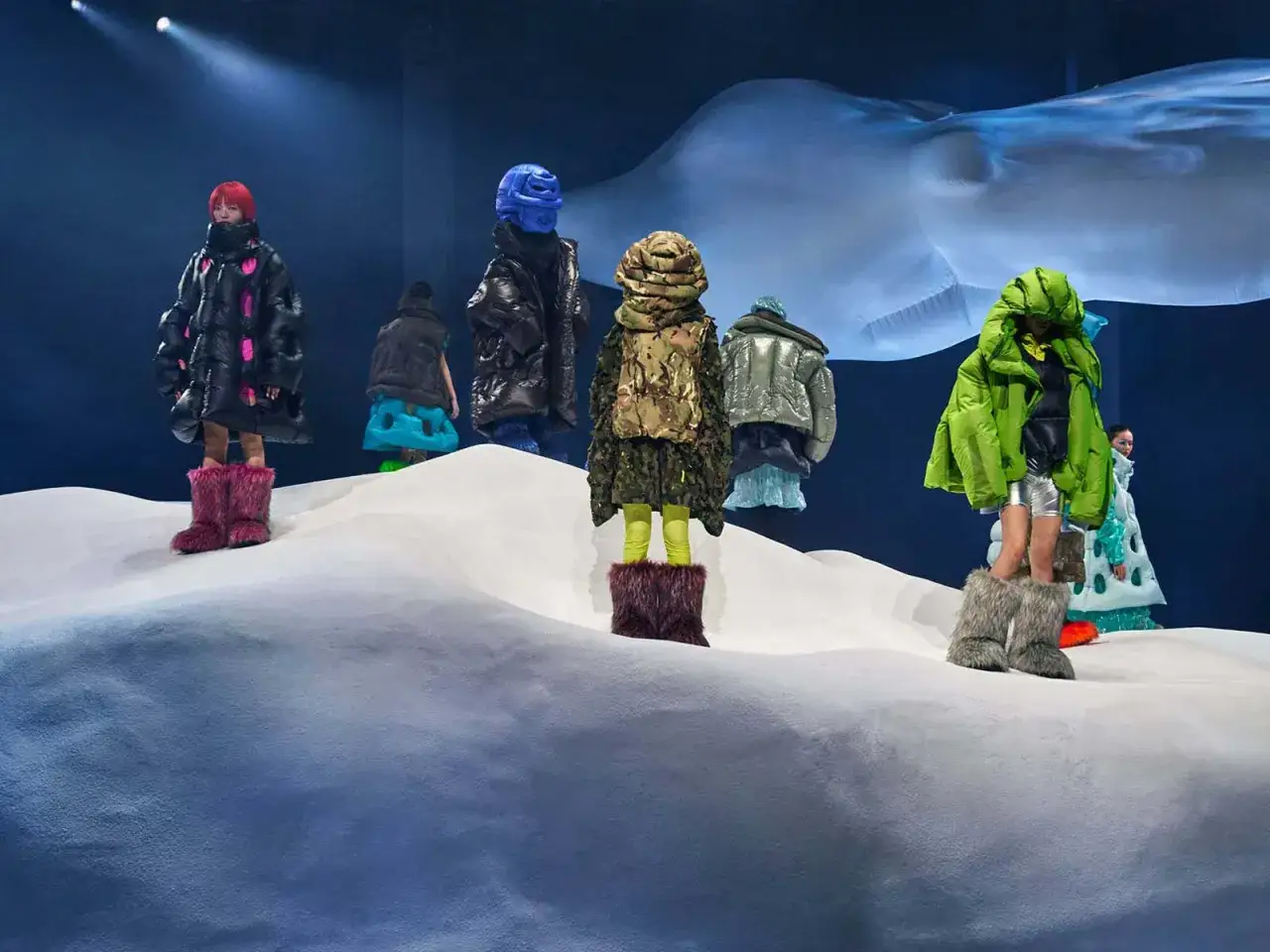 Dingyun Zhangs Models präsentieren auf einer Schneelandschaft voluminöse, bunte Daunenjacken und auffällige Fellstiefel.