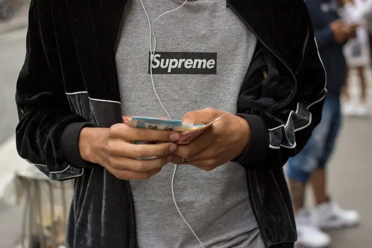 Person in Supreme T-Shirt zählt Geld. Was ist Supreme? Ein Lebensgefühl, das sich in Streetwear und dem Wunsch nach dem Besonderen ausdrückt.