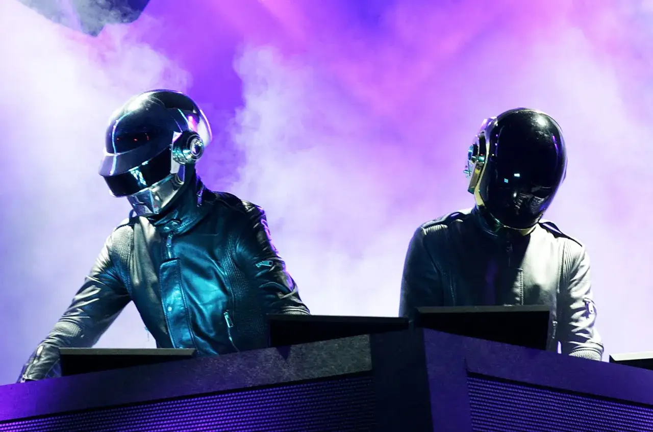 Zwei DJs mit Masken stehen hinter ihren Decks, im lila Nebel.