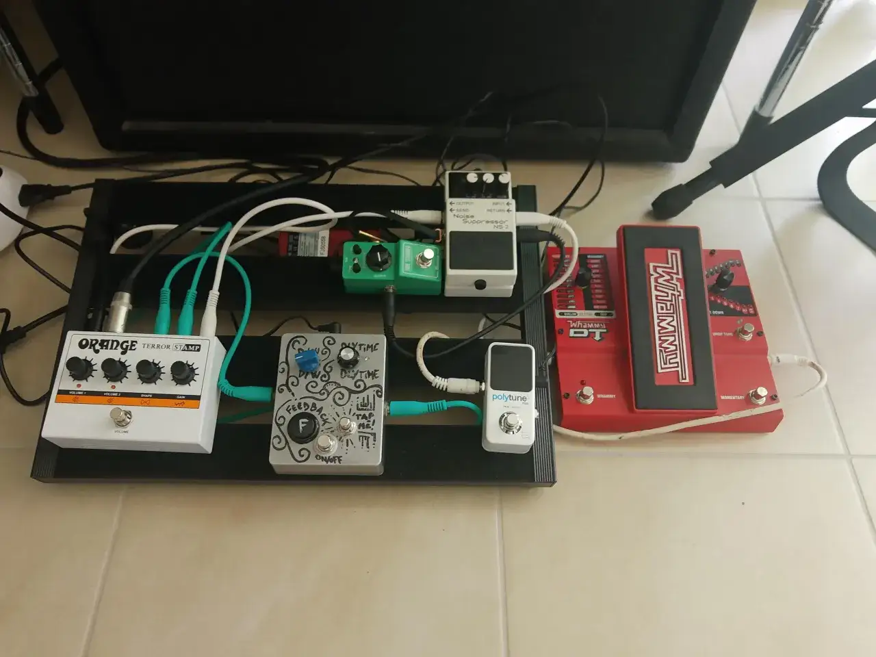 Ein Pedalboard mit einem wei&szlig;en Orange Terror Stamp, einem gr&uuml;nen Tube Screamer, einem silbernen Feedback-Pedal und einem roten Whammy DT.