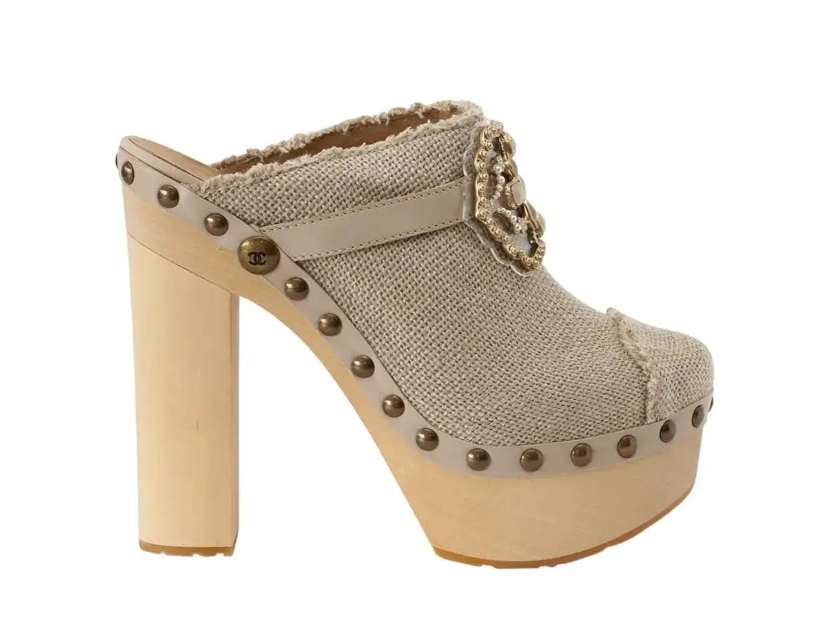 Ein eleganter Holz-Clog mit beige-farbenem Stoffbezug, Nieten und einer auff&auml;lligen Brosche. Diese teuerste Crocs der Welt sind ein modisches Statement.