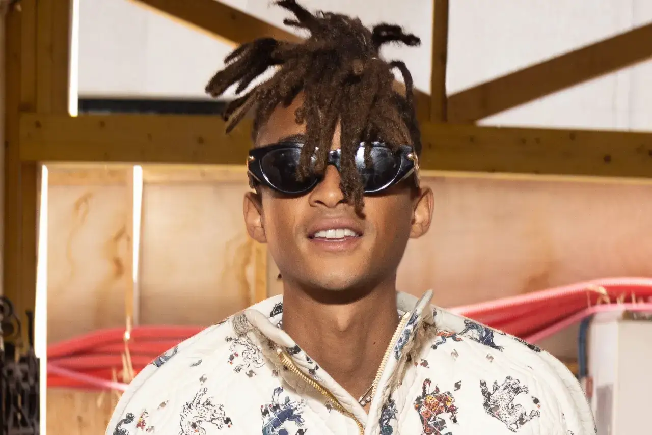 Jaden Smith heute mit Dreadlocks und Sonnenbrille, trägt eine gemusterte Jacke.