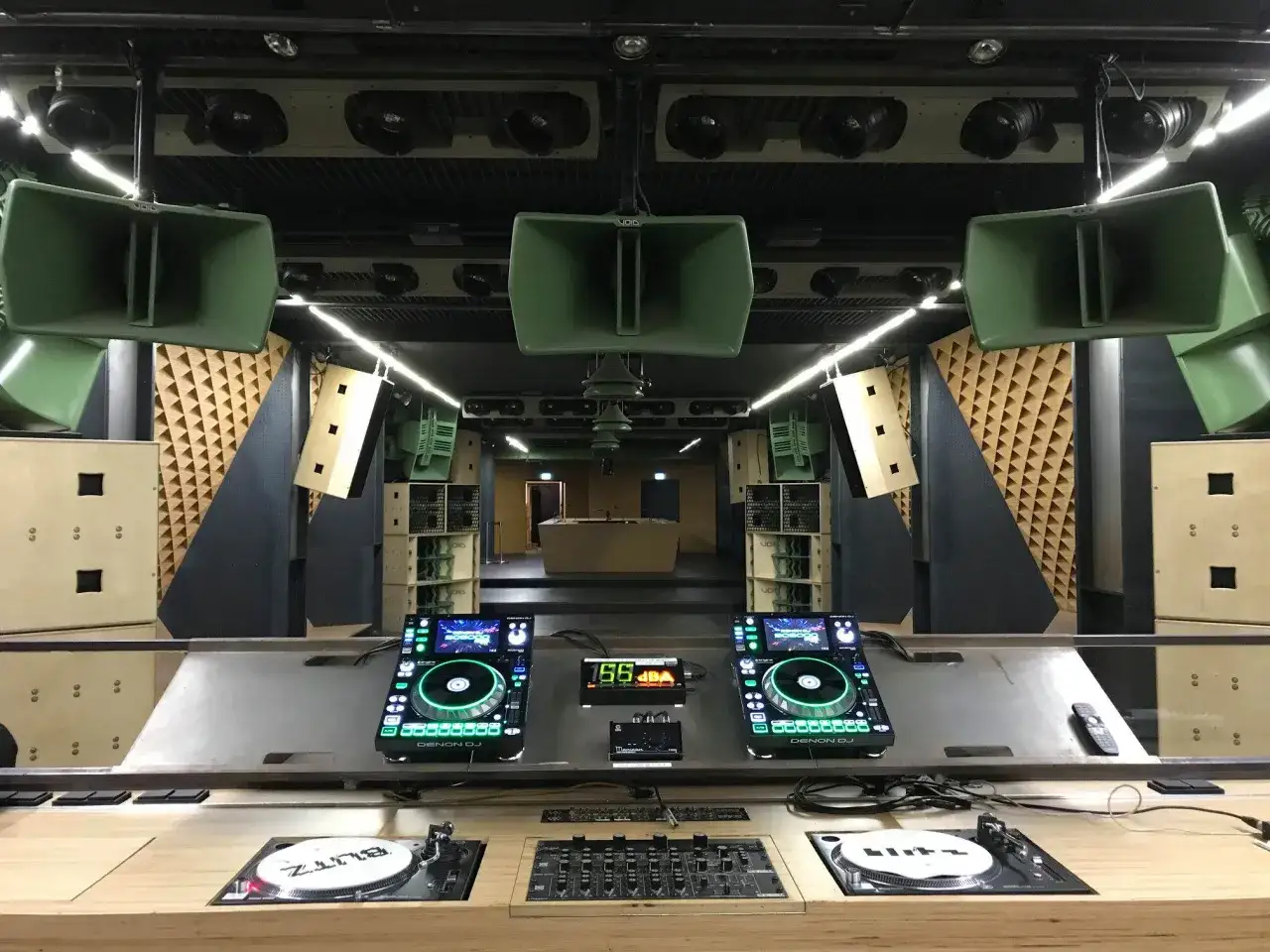 DJ-Pult mit zwei Denon-Decks, Turntables und vielen grünen Lautsprechern. Bereit für fette DJ-Musik.