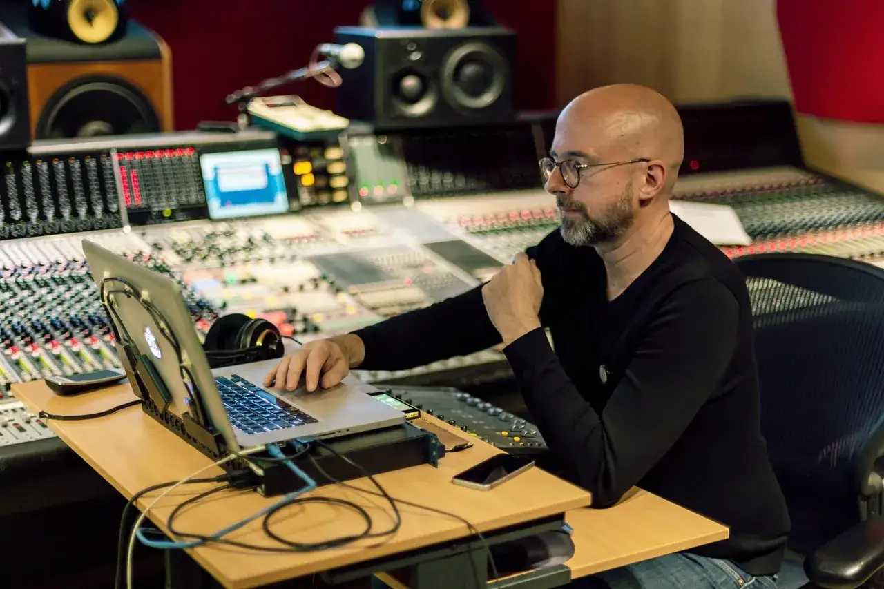 Hans Martin Buff sitzt an einem Mischpult, arbeitet am Laptop und hört Musik.